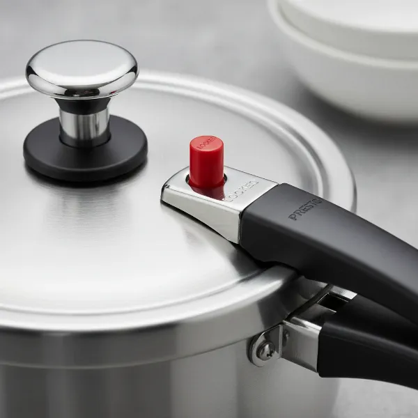 Close-up of Presto pressure cooker lid showing regulator, cover lock indicator, and ergonomic handle.